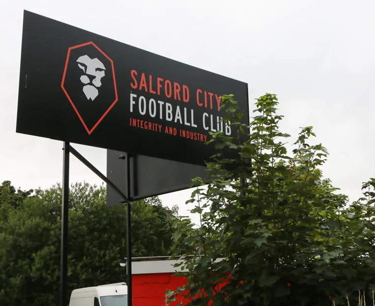 Biển hiệu chính thức của câu lạc bộ Salford City FC, đánh dấu sự hiện diện của đội bóng bên ngoài sân Moor Lane.