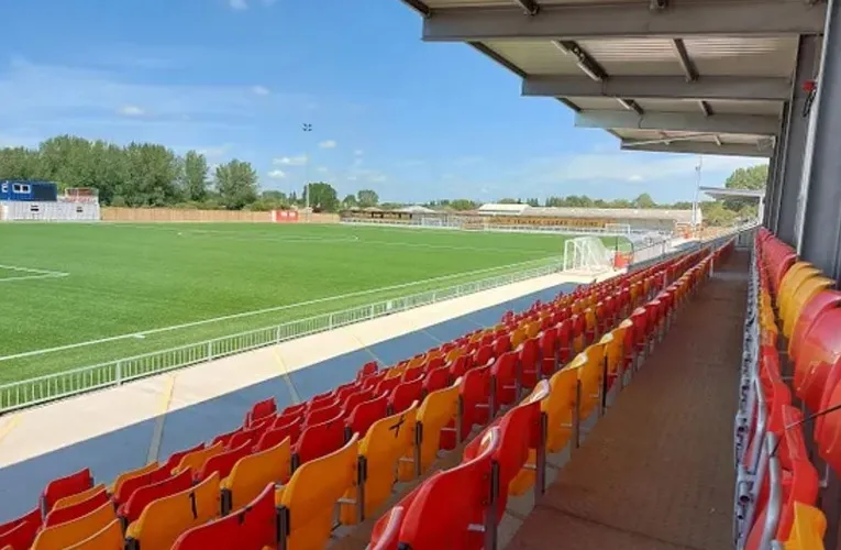 Góc nhìn toàn cảnh sân Meadow Park Gloucester từ khán đài, thể hiện sân cỏ nhân tạo và khu vực đứng, mang đến trải nghiệm gần gũi cho người hâm mộ