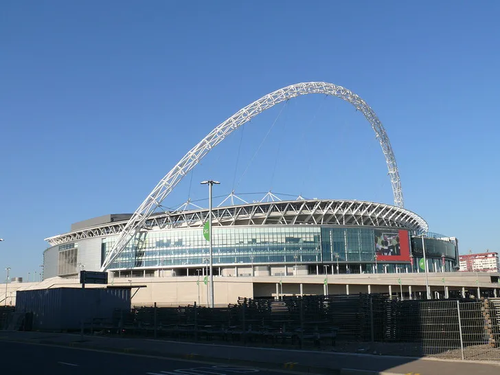 Toàn cảnh mặt ngoài sân vận động Wembley trong ánh nắng, thể hiện kiến trúc vĩ đại